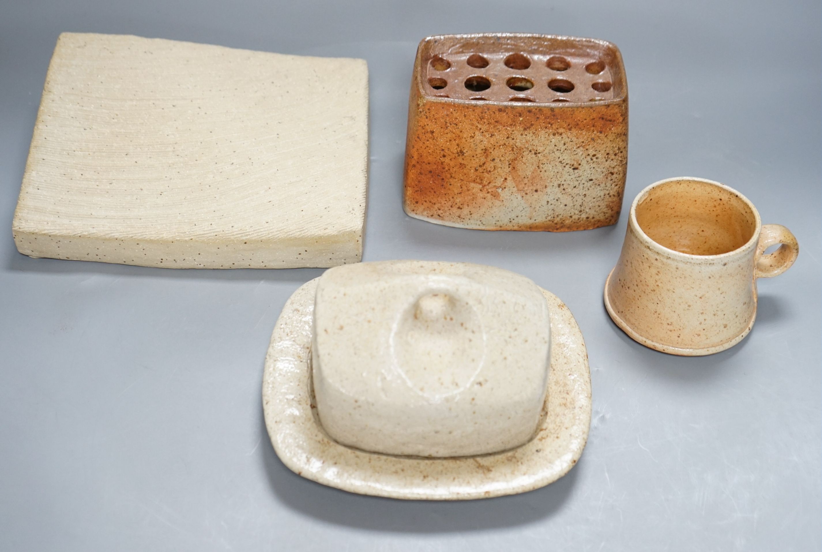 Sarah Walton (b.1945), a salt glazed stoneware flower brick, together with a salt glazed butter dish and cover, a similar mug, and a ‘Field’ horizontally carved linear slab, 22cm wide, all with impressed marks, (4)